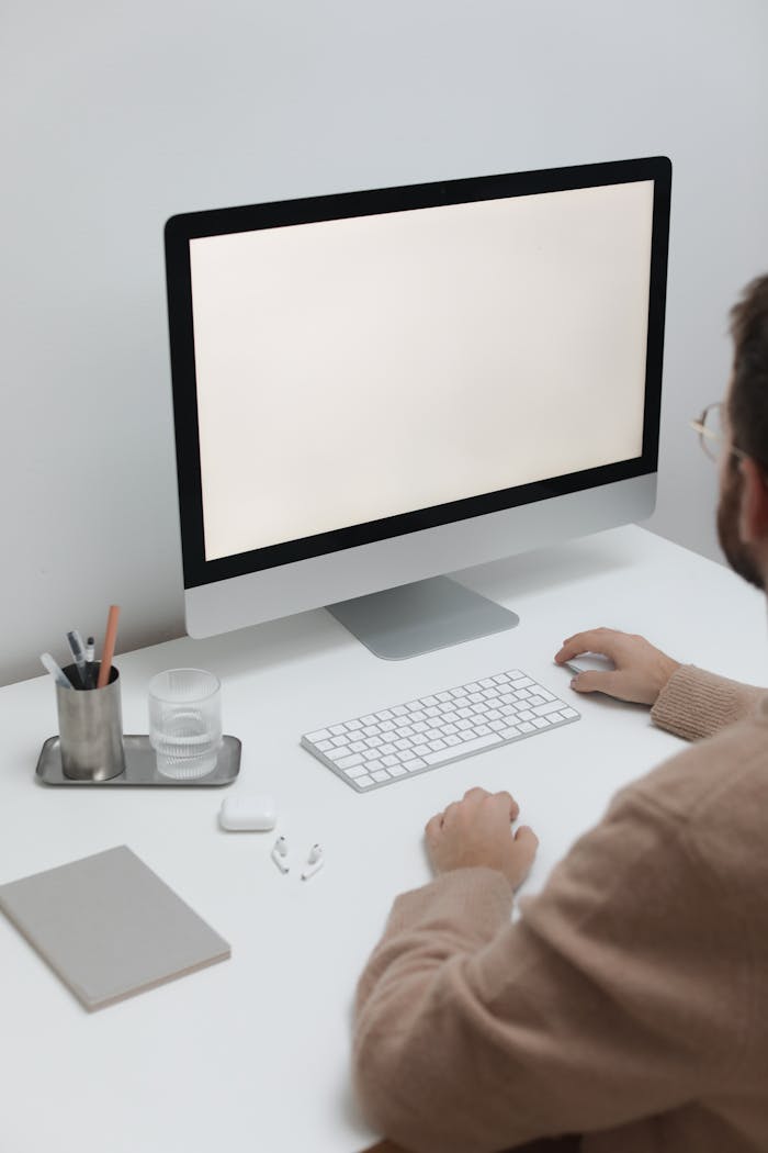 A man working at a minimalist desk with a blank computer screen, stylized for modern office themes.